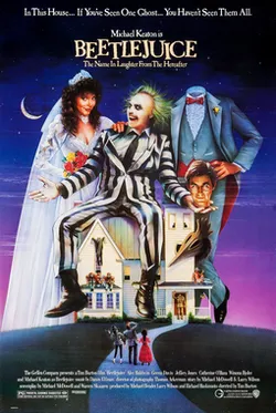 Three people dressed as a bride, groom, and moster are sitting on top of a house with smaller characters looking up at them from the ground